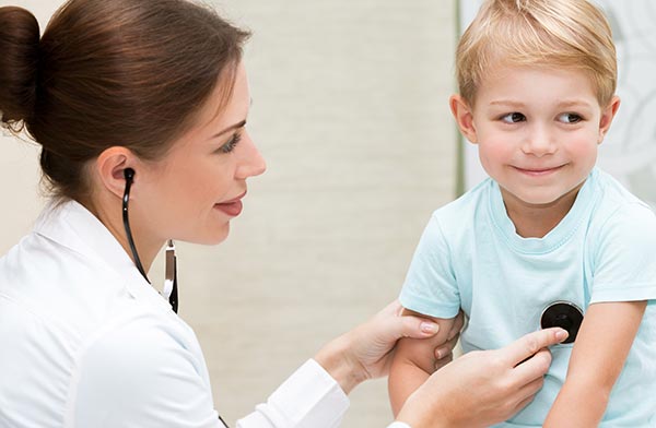 female doctor examining a smiling child